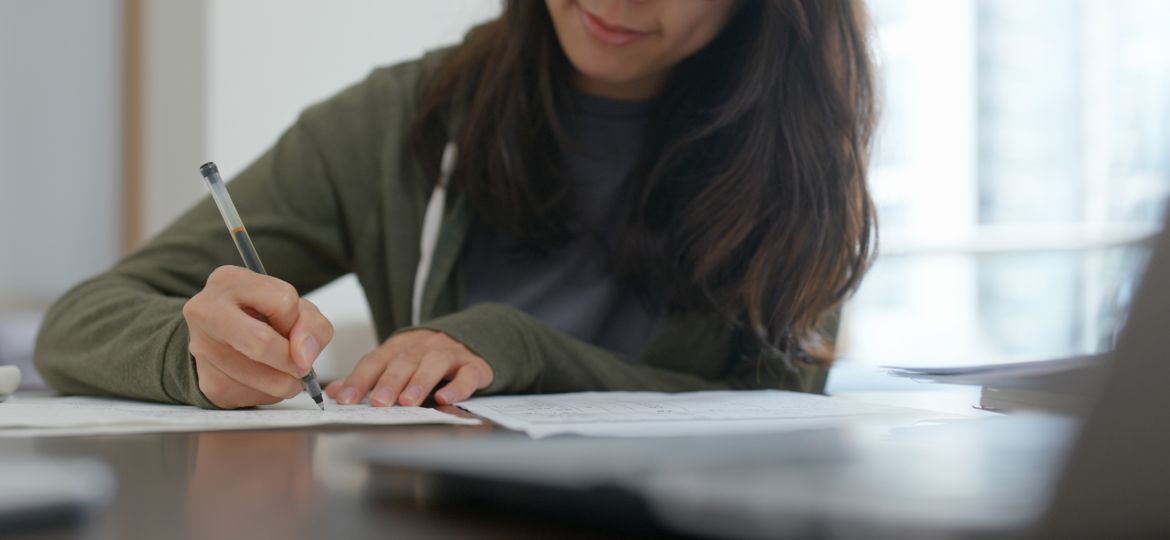 Woman write on the report, study for the exam at home